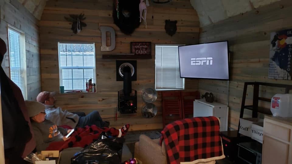 Cabin living room with pine walls and the wood stove lit