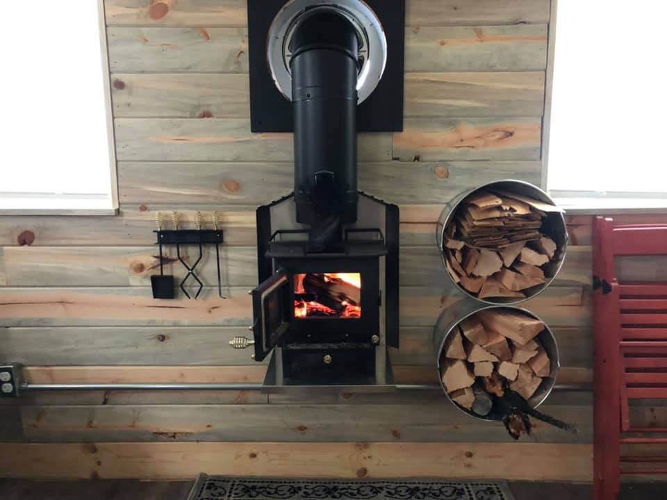 Wood stove burning with buckets of split firewood beside it