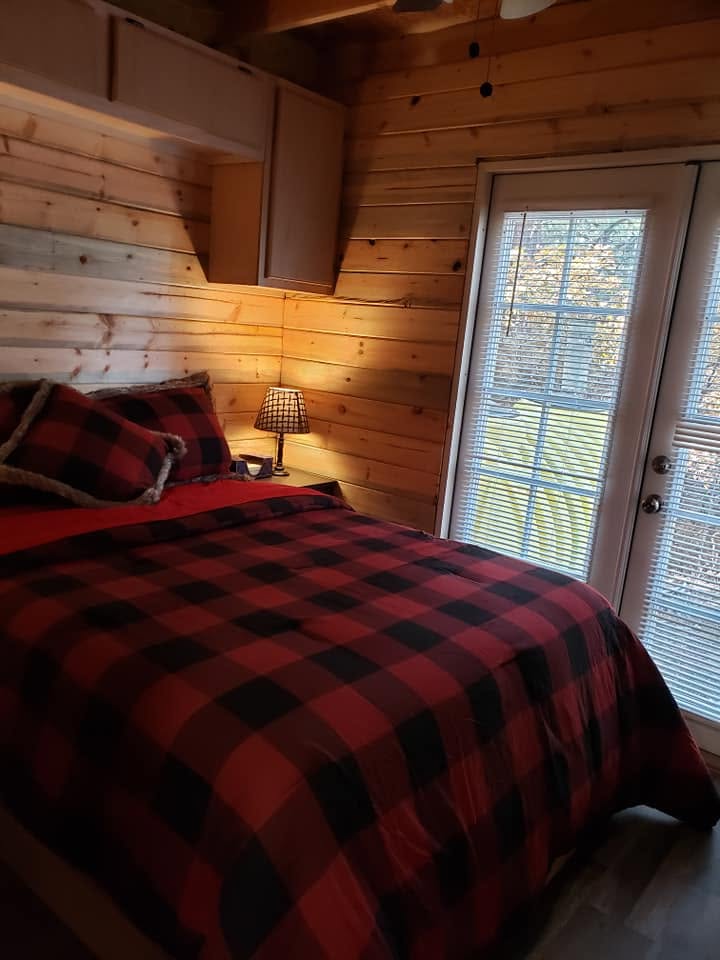 Bedroom with red buffalo plaid bedding and a french door to the deck